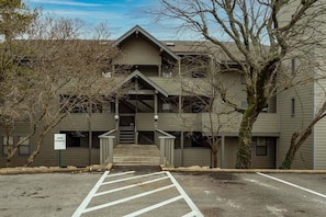 A building with a central entrance, a sign indicating open parking, and a staircase leading to the entrance.