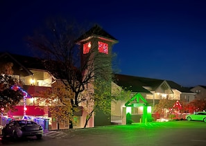 Un edificio residenziale con una struttura a torre e un ingresso illuminato di verde.