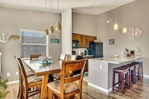 A modern kitchen with wooden cabinets, a central island with bar stools, and pendant lighting.