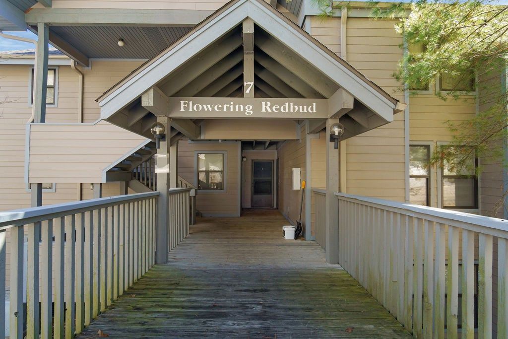 A covered walkway leading to a building with a sign reading 'Flowering Redbud.'