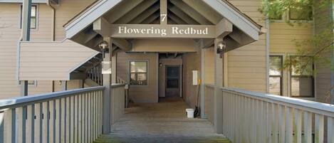 A covered walkway leading to a building with a sign reading 'Flowering Redbud.'
