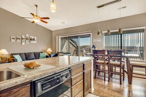 Una cocina moderna con una isla grande, lavavajillas y un comedor con sillas de madera y una mesa.