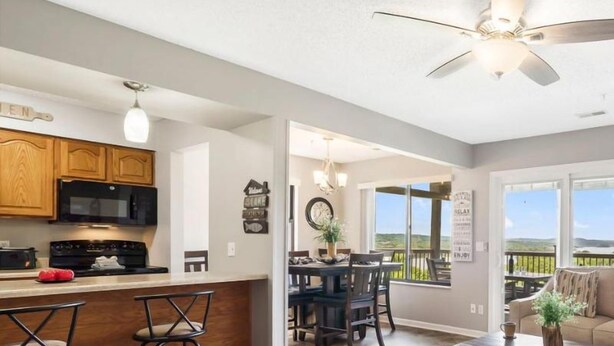 A modern kitchen with a bar area, dining space, and a balcony with a view. - Lake View Condo, Spacious & Only 1 Mile to Silver Dollar City – 1204 (Branson)