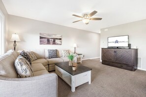 A modern living room with a sofa, coffee table, and a TV mounted on the wall. - Lake View Condo, Spacious & Only 1 Mile to Silver Dollar City – 1204 (Branson)