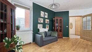 Una habitación con un sofá gris, armarios de madera, una planta en maceta y obras de arte en la pared.