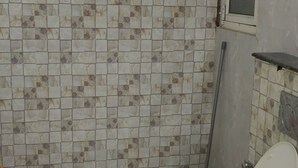 Een badkamer met toilet, douche en betegelde wand.