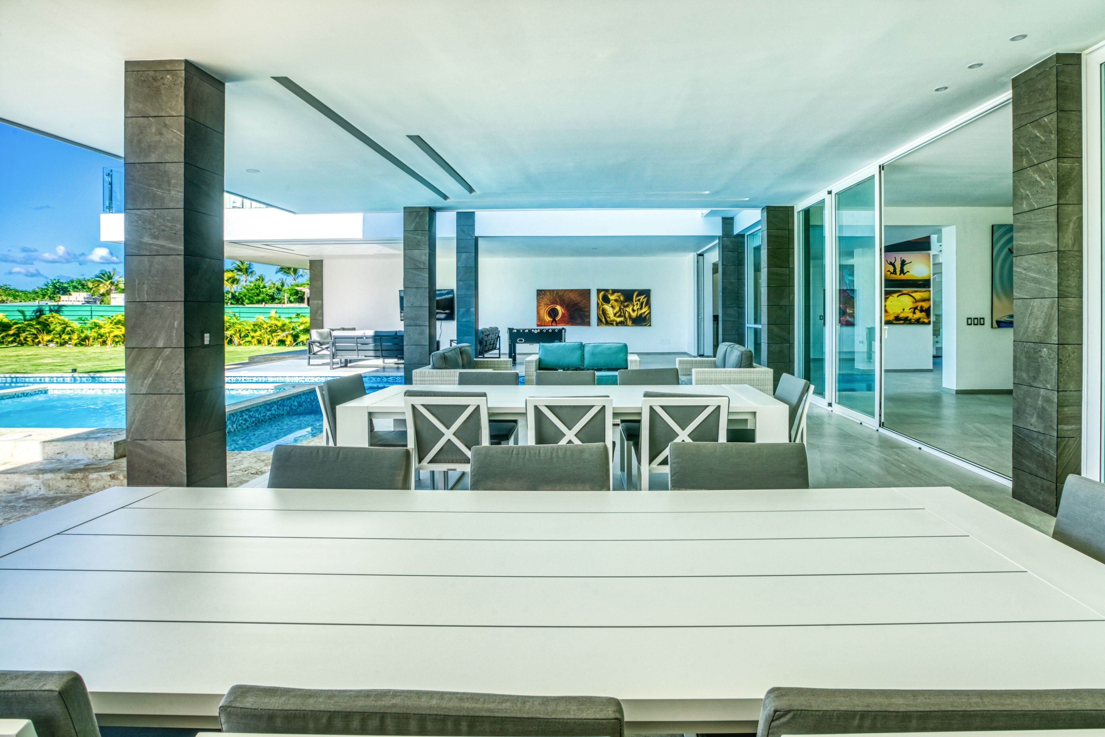 A modern outdoor dining area with a pool view, large windows, and contemporary furniture.