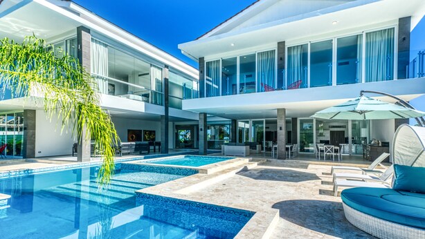 A modern two-story house with a swimming pool, outdoor seating, and a large glass window. - Modern and Fresh Oceanfront Villa (Punta Cana)