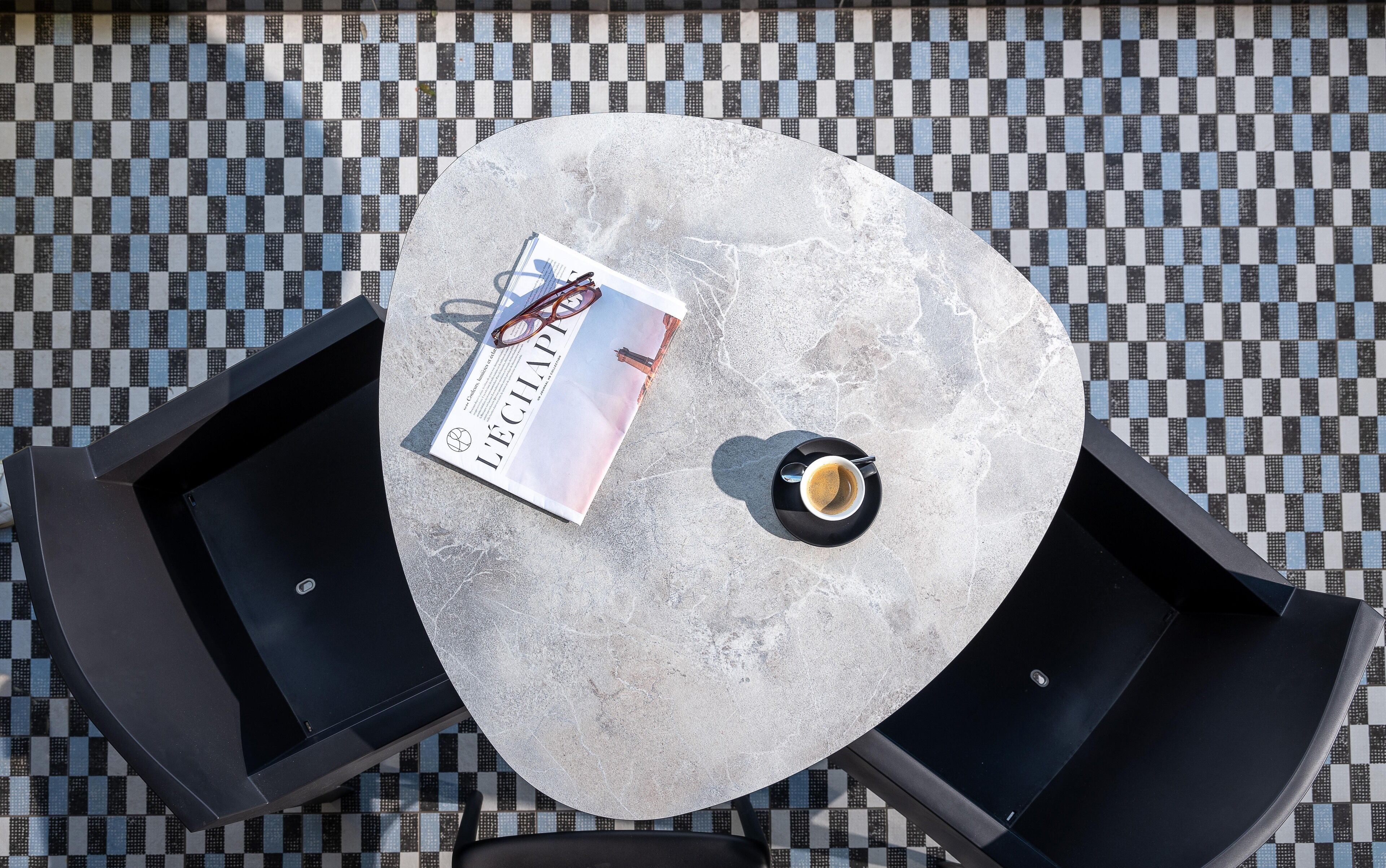 Un tavolo rotondo con una rivista, un paio di occhiali e una tazza di caffè.