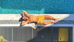 A man lying on a poolside lounge chair with a checkered pattern. - 3 Pines Design Living (Heraklion)