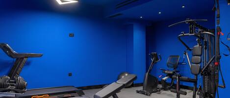 Un gimnasio con equipo de ejercicio, una cinta de correr y una banca.