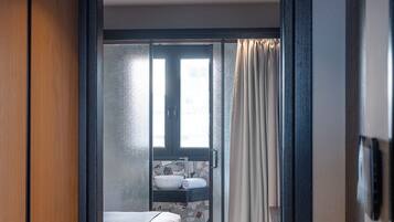 A hotel room with a bed, a bathroom with a sink and a mirror, and a view through a glass door.