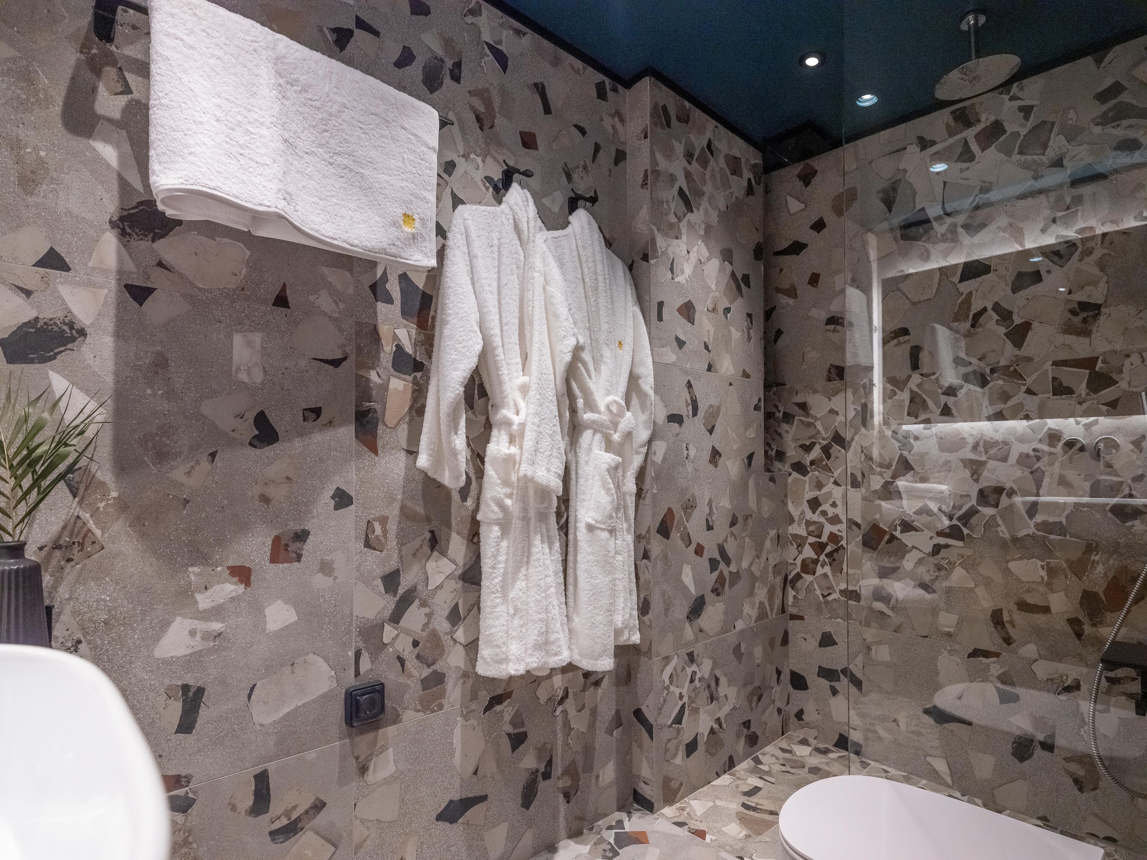 Un bagno con parete in mosaico, una vasca da bagno bianca e un portasciugamani con asciugamani bianchi.