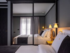 A modern hotel room with a large bed, a bedside table, and a mirror.