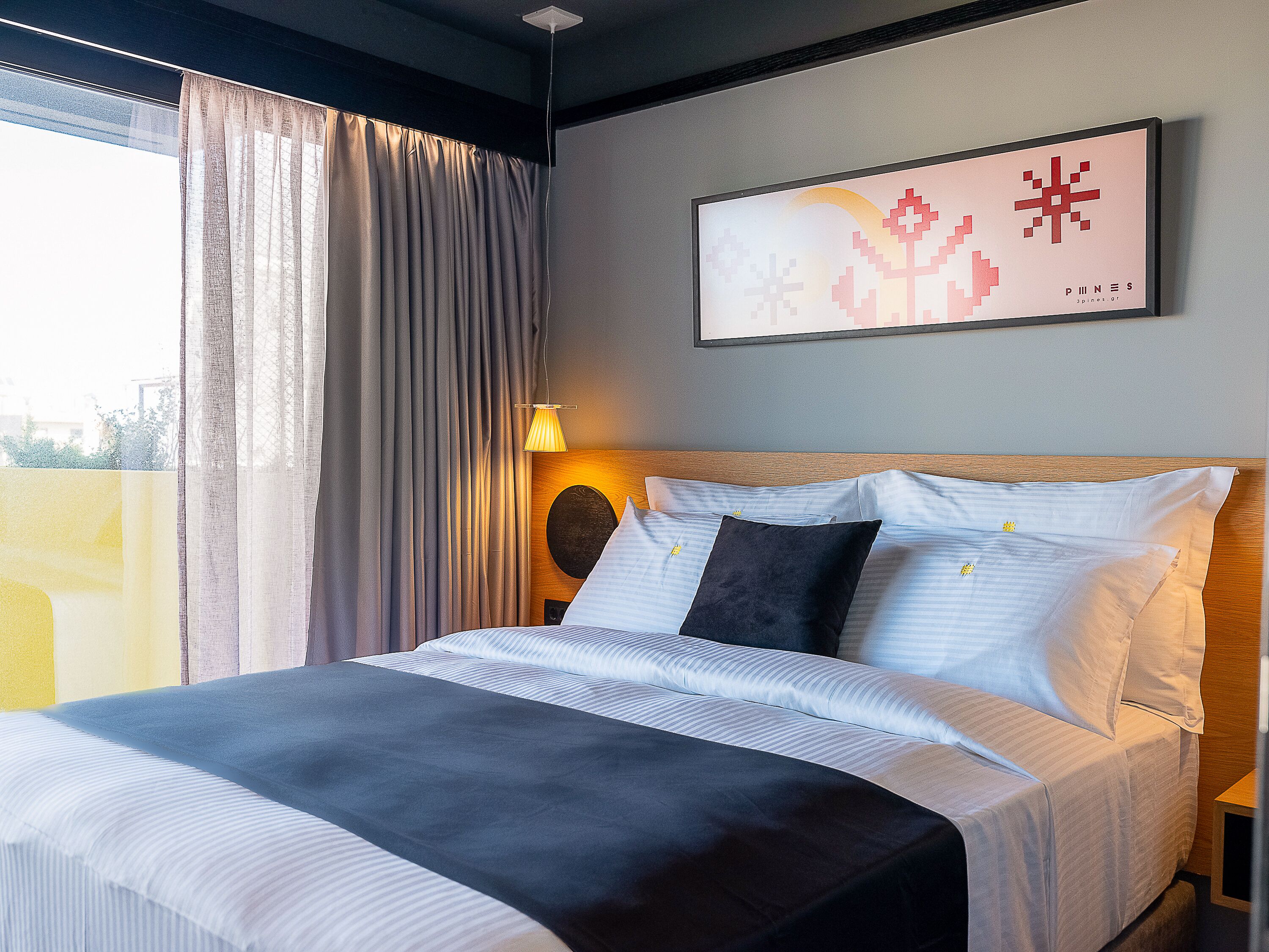 A modern hotel room with a large bed, a headboard with a circular design, and a view of the city through the window.