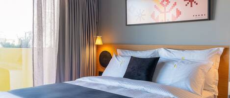 A modern hotel room with a large bed, a headboard with a circular design, and a view of the city through the window.