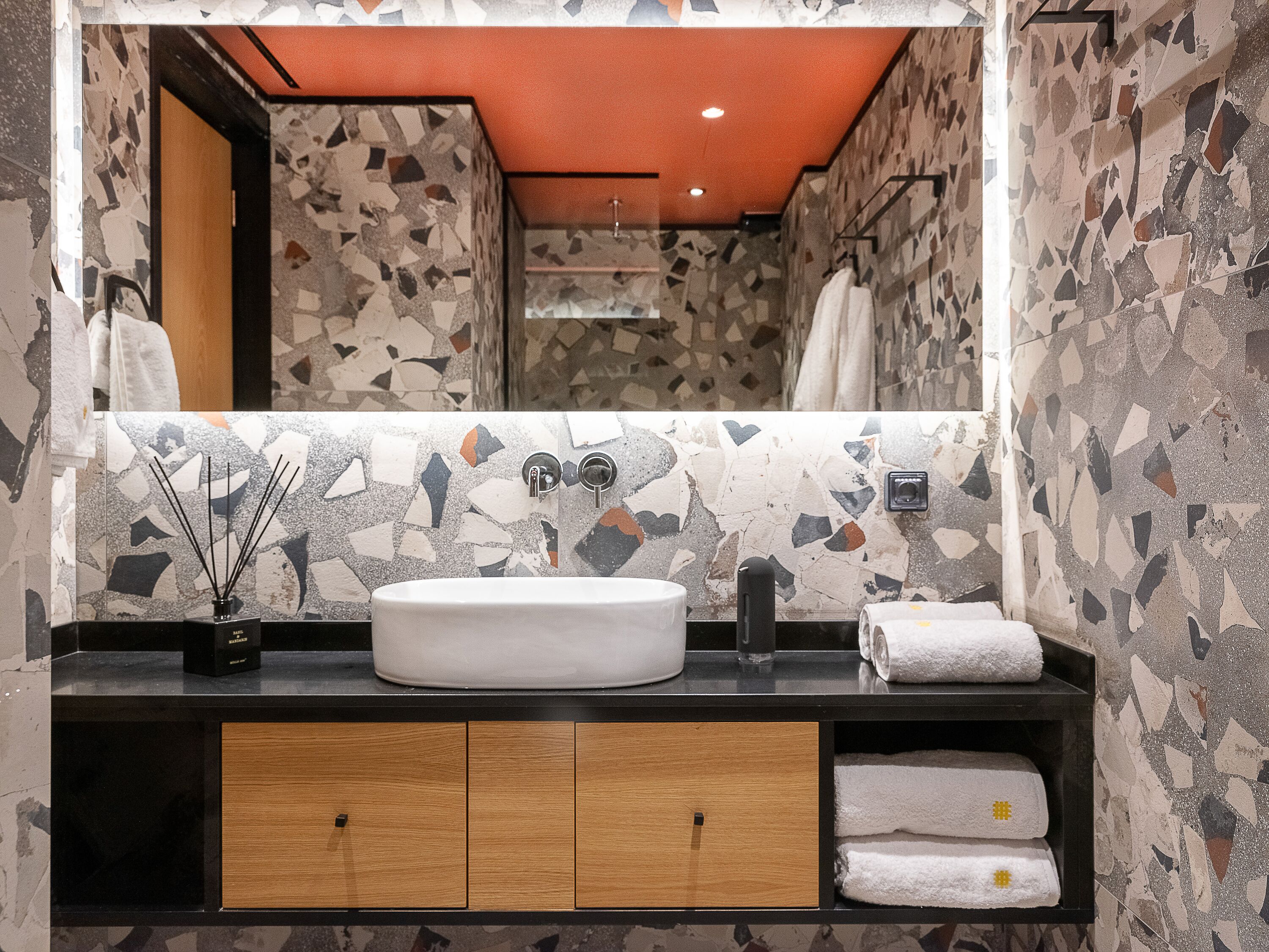 A bathroom with a white sink, a mirror, and a tiled wall.