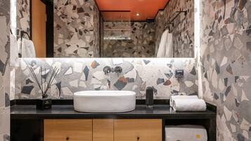 A bathroom with a white sink, a mirror, and a tiled wall.