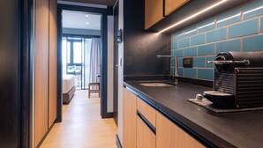 A modern kitchen with wooden cabinets, a black countertop, and a coffee machine. - 3 Pines Design Living (Heraklion)