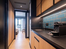 A modern kitchen with wooden cabinets, a black countertop, and a coffee machine.