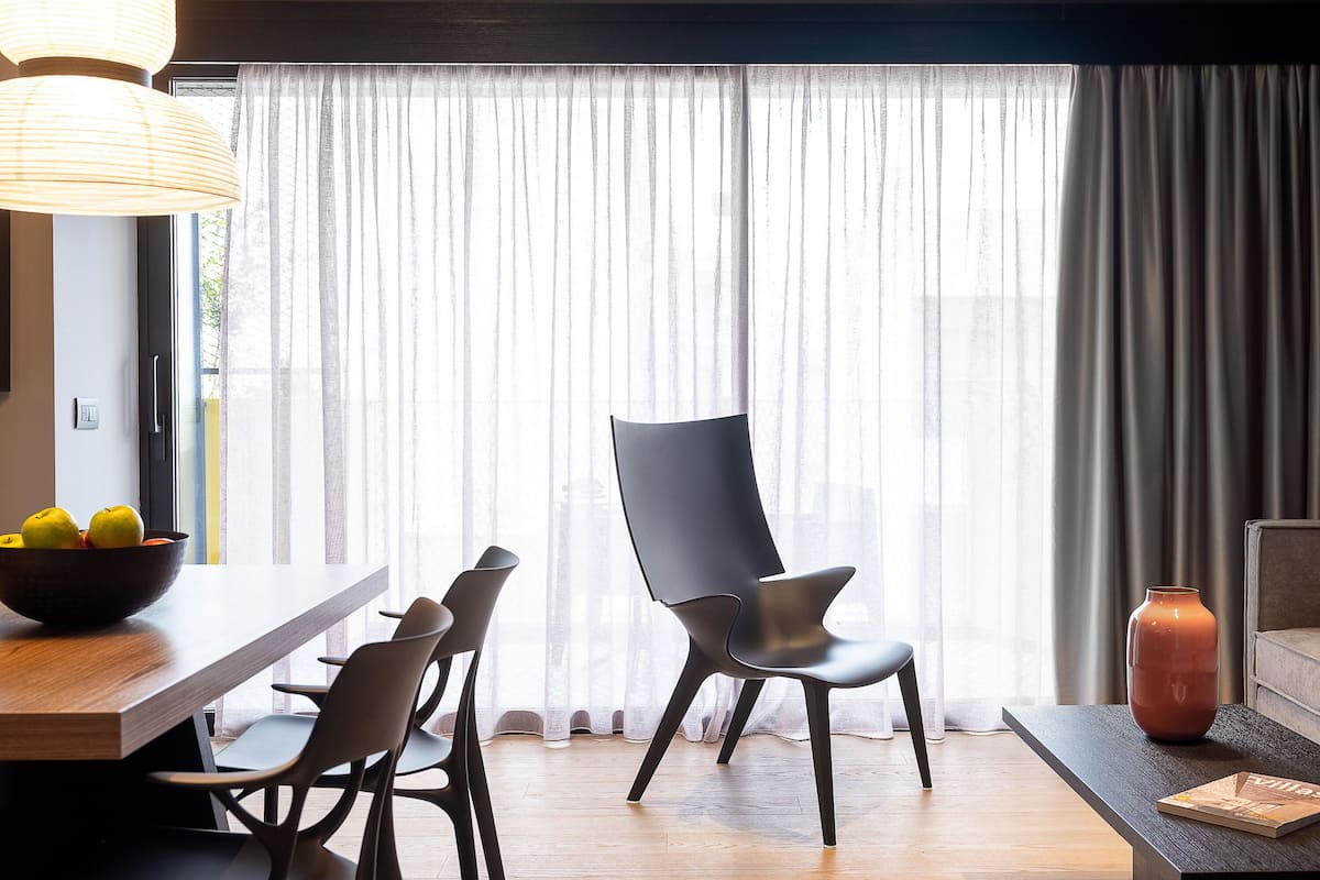 A modern dining area with a wooden table, black chairs, and a bowl of fruit.