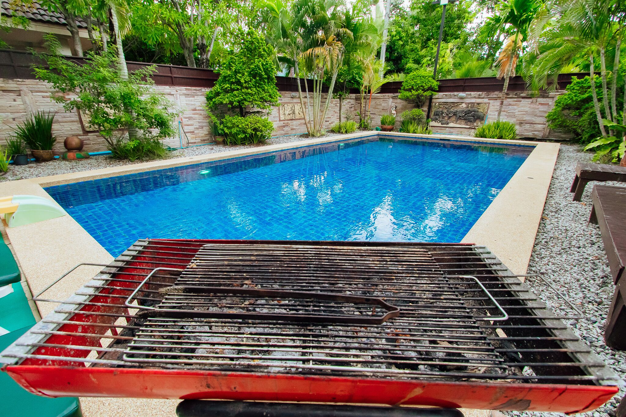 A swimming pool with a grill in the foreground.