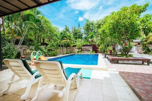 Un área de piscina con sillones de descanso y una pequeña terraza.