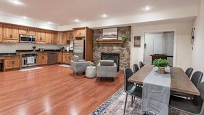 A spacious kitchen with wooden cabinets, a stone fireplace, and a dining area with a long table and chairs.