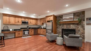 A modern kitchen with wooden cabinets, stainless steel appliances, and a stone fireplace.