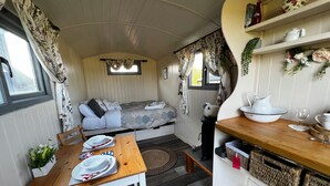 Un intérieur de camping-car confortable, avec un lit, une table à manger et un coin cuisine.