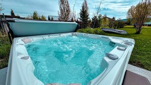 Un bain à remous doté d’un siège intégré, entouré d’une pelouse et d’arbres.