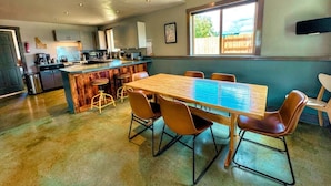 Une cuisine spacieuse équipée d’appareils modernes, un coin repas avec une table et des chaises en bois, et une grande fenêtre qui laisse entrer la lumière naturelle.