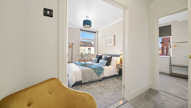 Een slaapkamer met een bed, nachtkastje, lamp en uitzicht.