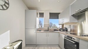 Een moderne keuken met witte kasten, een zwarte oven en een raam dat natuurlijk licht binnenlaat.