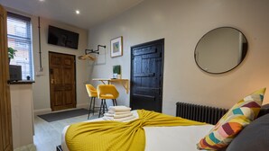 Een slaapkamer met een bed, een bureau, een stoel, een spiegel en een deur.