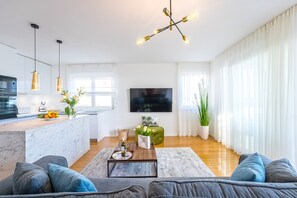 Una sala de estar moderna con sofá, mesa de centro y una zona de cocina con encimera de mármol.