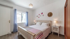 A bedroom with a bed, bedside tables, a window with curtains, and wall decorations. - C22 Quinta do paraiso Superbly Appointed and Furnished Bungalow (Carvoeiro)