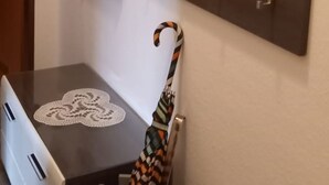 A compact room with a dark wooden desk, a white chair, a large mirror, and a coat rack with hangers. - Vacation apartment in house Norderney No.24 (Dornum)