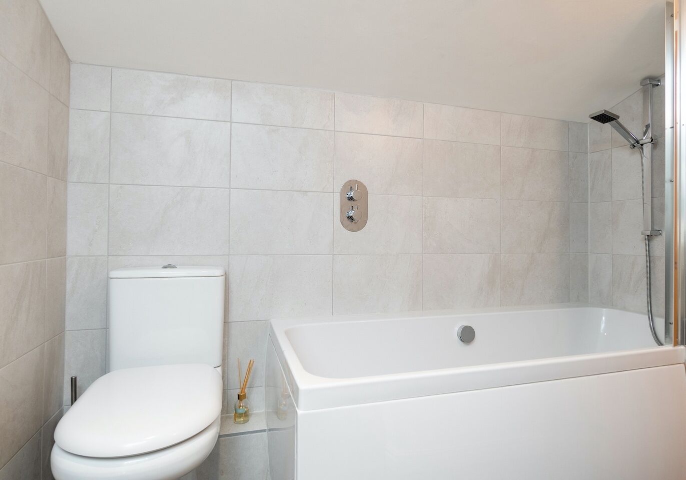 A modern bathroom with a toilet, a bathtub, and a shower.
