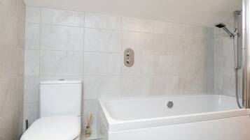 A modern bathroom with a toilet, a bathtub, and a shower.