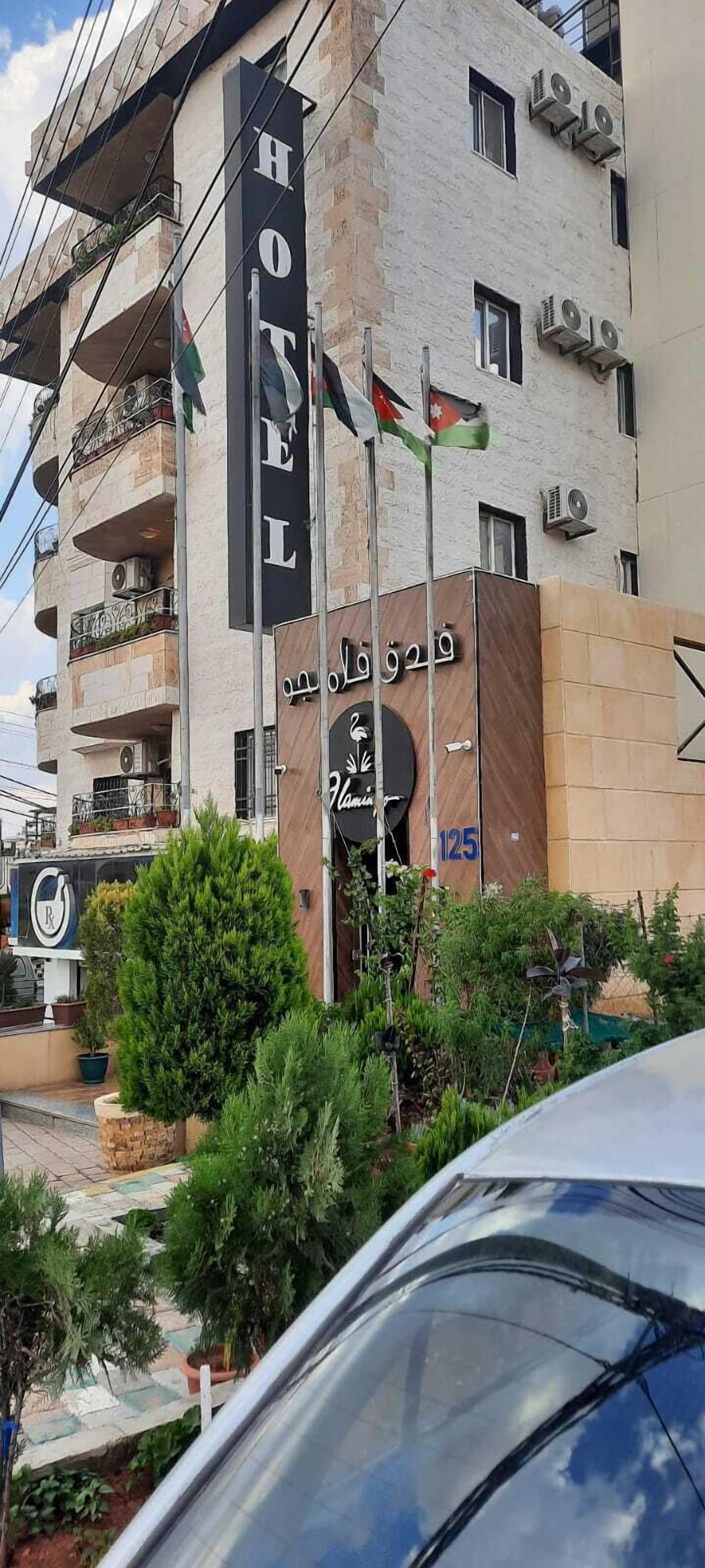 Ein Hotel mit Balkonen, einer Flagge und einem Schild mit arabischer Schrift.