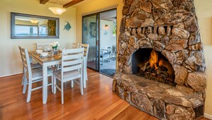 A dining area with a stone fireplace, wooden dining table, and chairs. - Bluewater Retreat - Ocean Views from the heart of Santa Barbara (Santa Barbara)