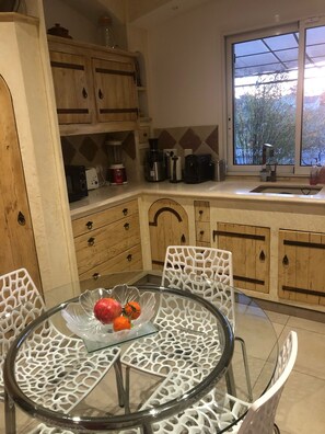 Enjoy cooking in this well-equipped kitchen with a round table, wooden cabinets, and a window offering a view of the outdoors.