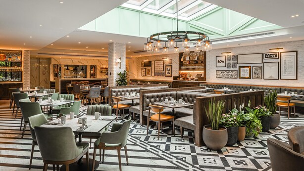 A spacious restaurant with high ceilings, a skylight, and a variety of seating options including booths and tables. - The Fellows House Mews (Cambridge)