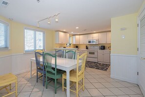 A kitchen with white cabinets, a dining table with chairs, and a microwave. - Luxury 5 Bedroom, 5 Bathroom mobility friendly, double condo with an outdoor rooftop pool, stylish decor  and free WiFi. Linens are included with this property. Just a Few Steps to the Beach! (Ocean City)