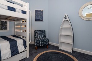 A bunk bed with a navy and white bedspread, a chair with an anchor pattern, a nautical-themed shelf, and a framed map on the wall. - Luxury 5 Bedroom, 5 Bathroom mobility friendly, double condo with an outdoor rooftop pool, stylish decor  and free WiFi. Linens are included with this property. Just a Few Steps to the Beach! (Ocean City)