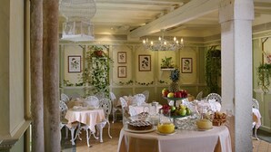 A dining area with white furniture, a chandelier, and a fruit display. - Hotel Casa Nicolo Priuli (Venice)