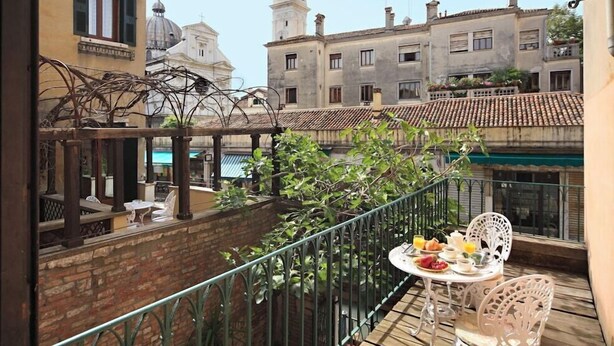 A balcony with a table set for breakfast, overlooking a cityscape with historic buildings and a church. - Hotel Casa Nicolo Priuli (Venice)