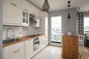 A modern kitchen with white cabinets, a wooden countertop, and a built-in oven. - Apartamenty City View od WroclawApartament-pl (Wroclaw)