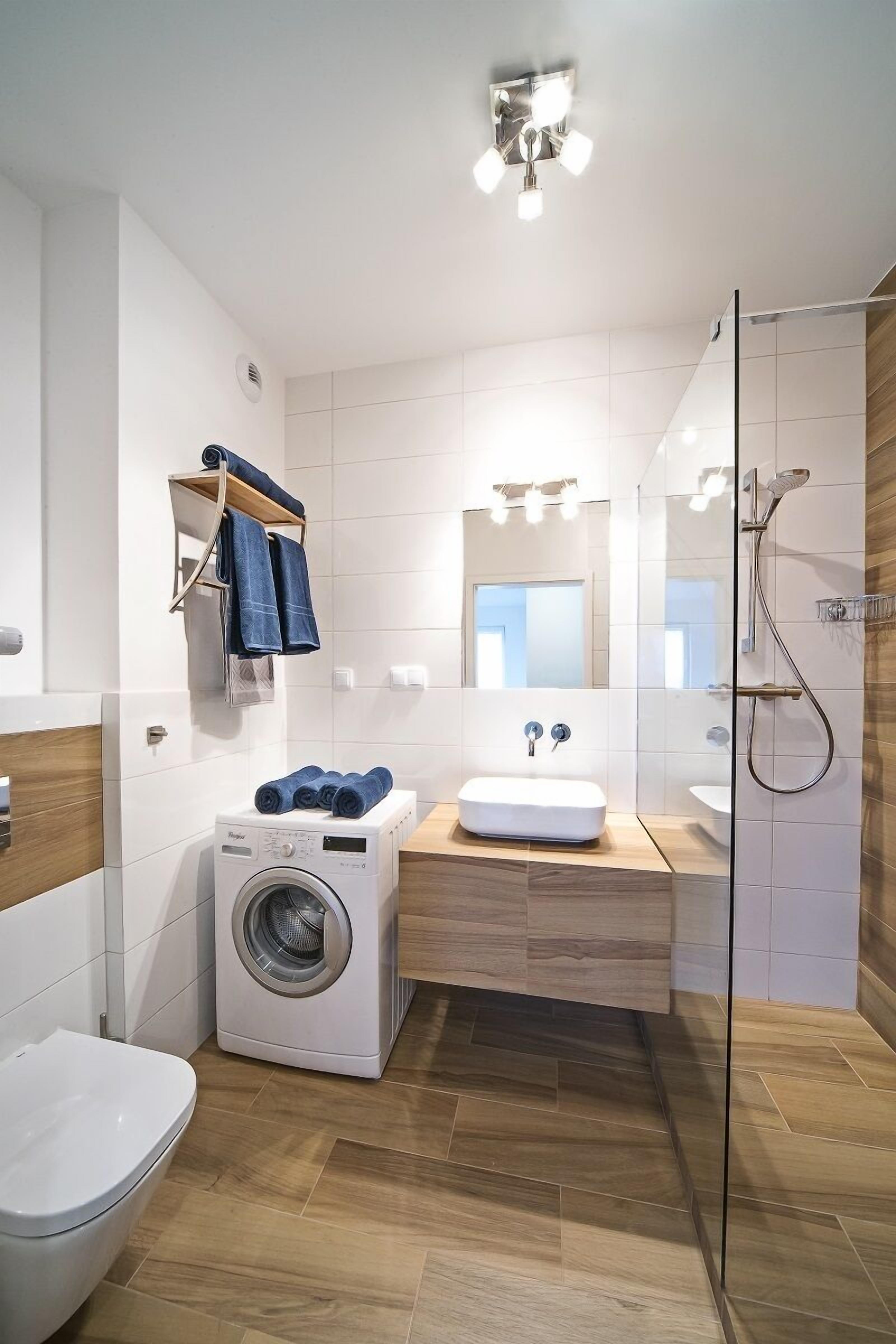Ein modernes Badezimmer mit Waschmaschine, Waschbecken und Dusche.
